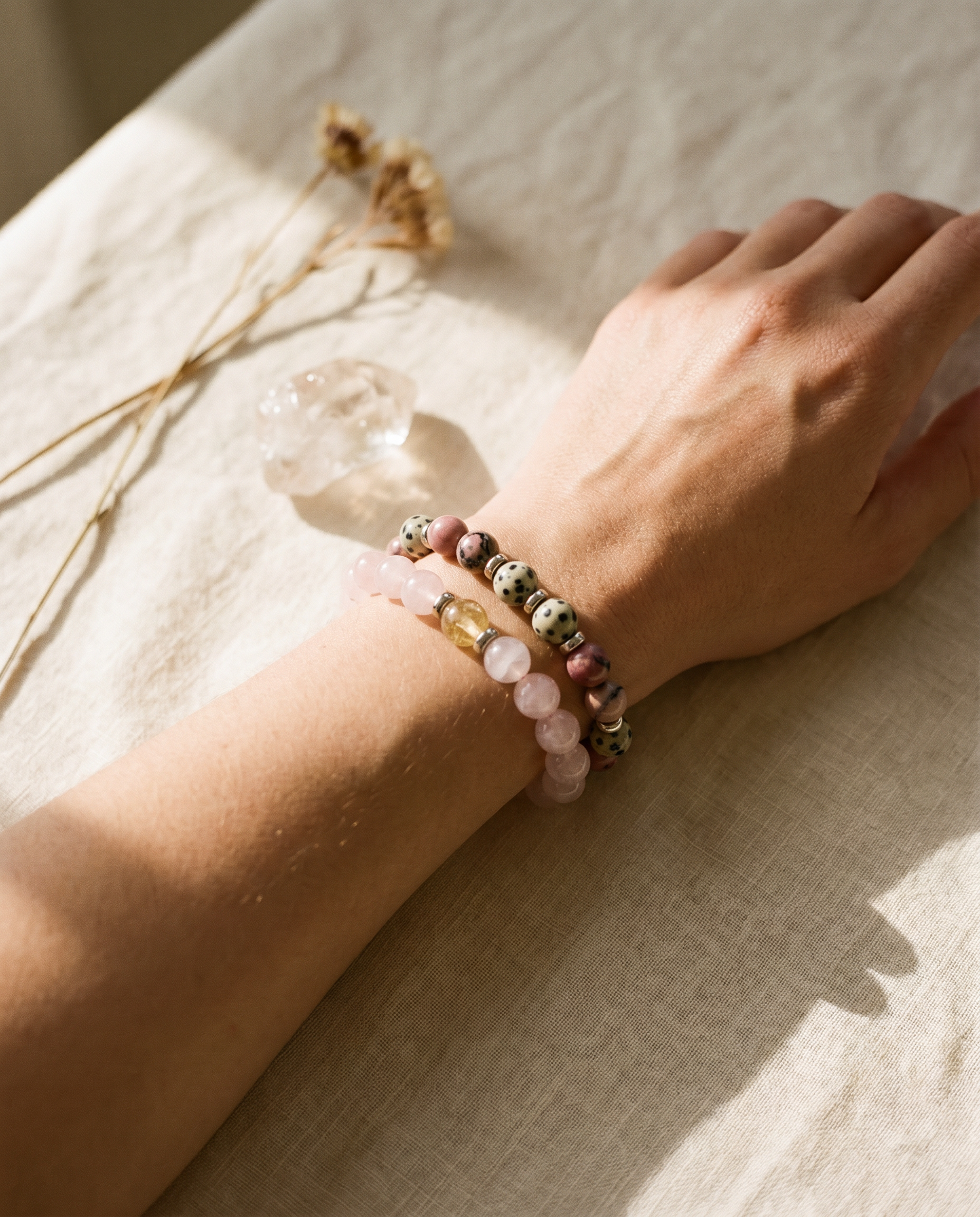 Hand wearing Evolve Mala crystal bracelets in soft natural light